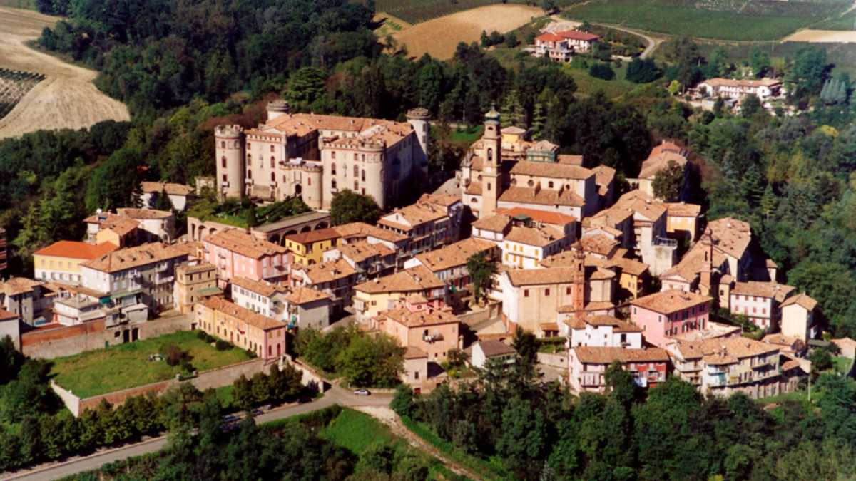 Vista aerea di borgo medievale in valle toscana con case in pietra serena, campanile, e monti boscosi sullo sfondo all alba