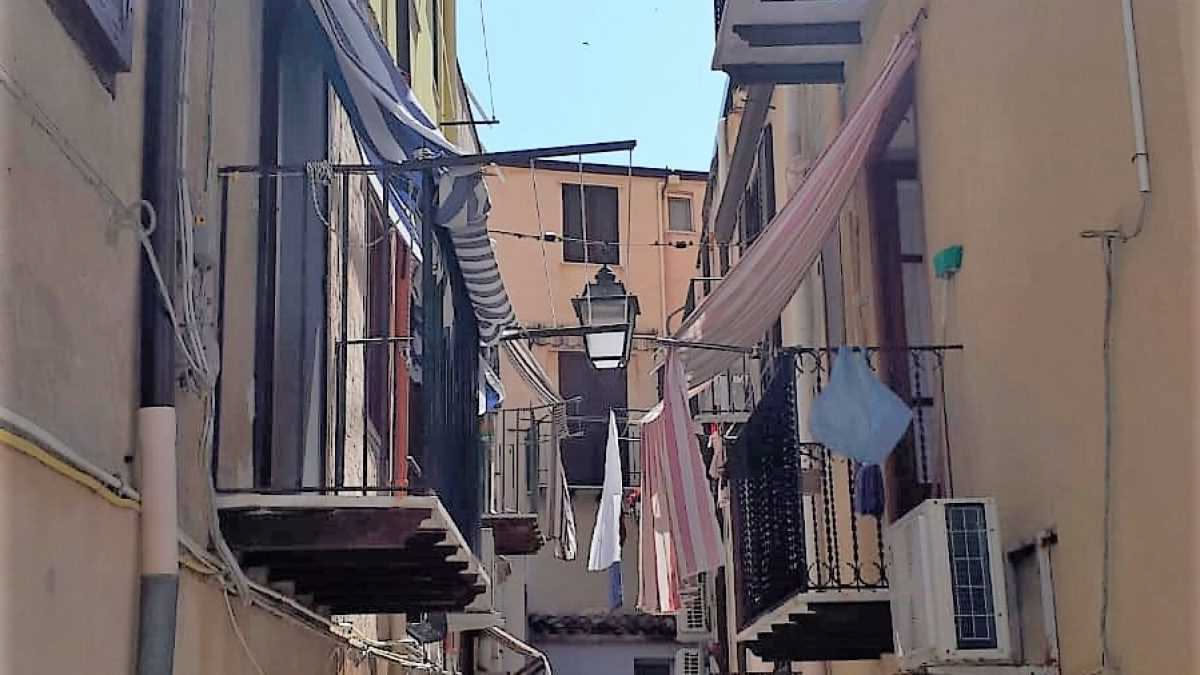 Stendibiancheria verticale bianco appoggiato nell angolo di una cucina in bilocale, con panni stesi in ordine e spazio libero davanti