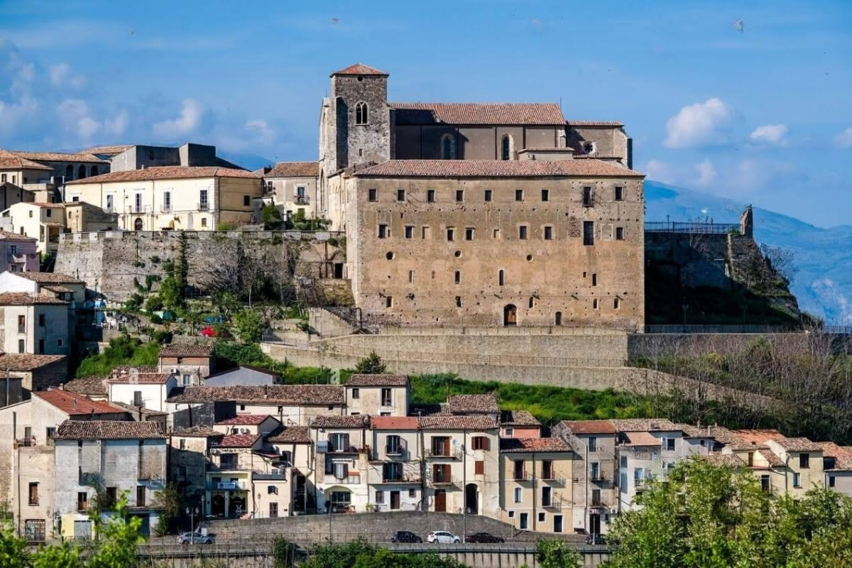 Piazza principale di Bevagna con edifici medievali in pietra, fontana centrale e cielo azzurro, vista del borgo antico umbro
