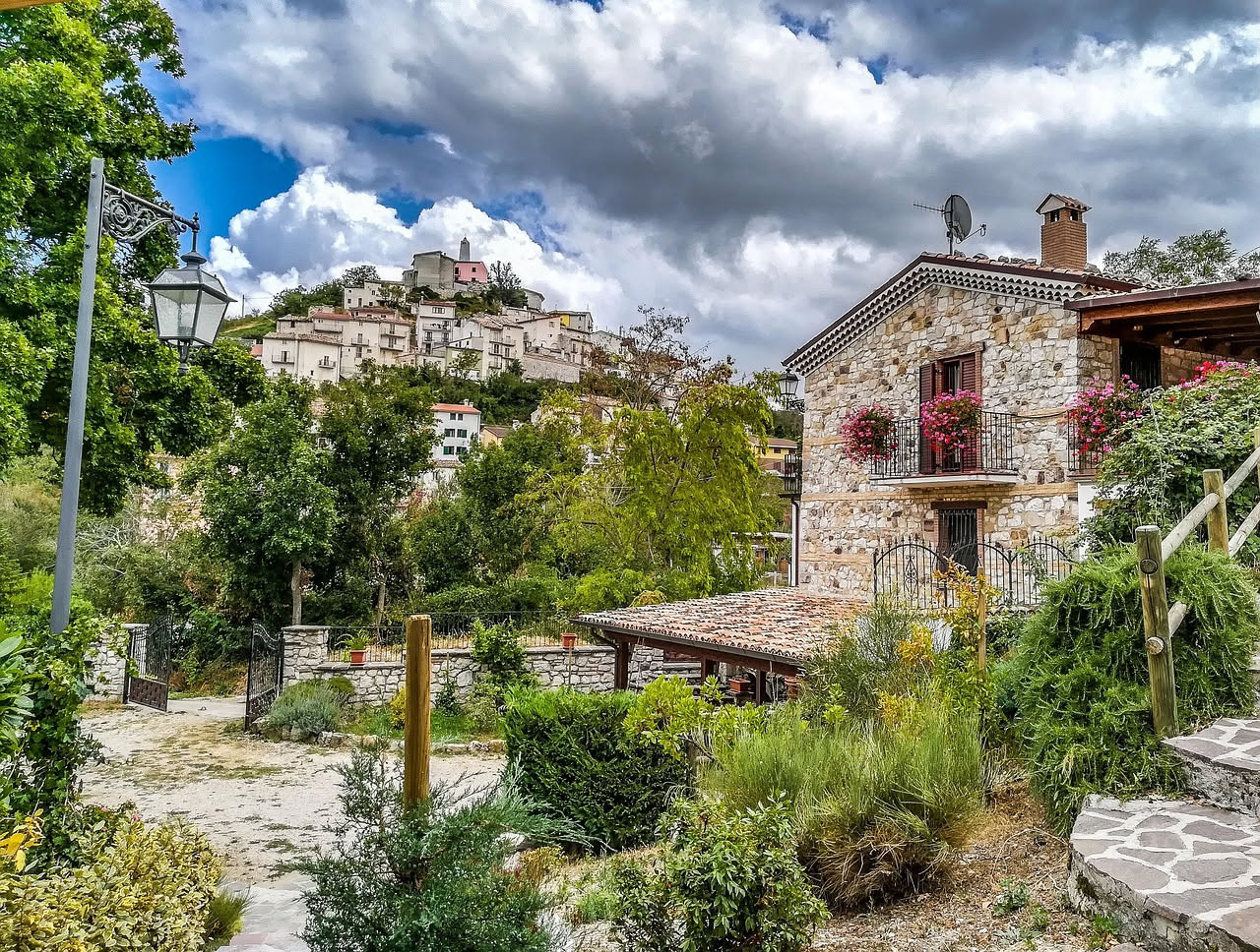 Petralia Soprana con le sue case in pietra costruite su un pendio, chiesa principale sullo sfondo e montagne delle Madonie all'orizzonte