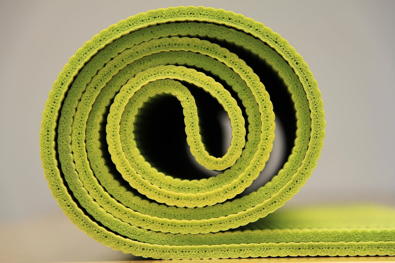 Rullo di schiuma per foam rolling appoggiato su un tappetino da palestra